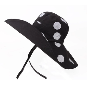 Detail of wide brim sun hat with white polka dots and adjustable black chin strap