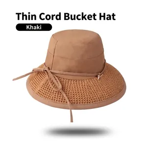 Detail of khaki bucket hat featuring woven straw brim and slim decorative rope with accents