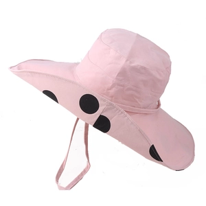 Detailed texture of pink wide brim sun hat with large black polka dots and chin strap