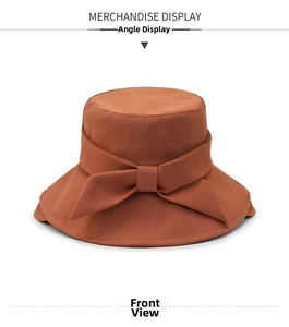 Detail of caramel dome bucket hat featuring a large elegant bow and textured fabric
