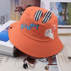 Detail of orange kids sun hat with bunny ears and adjustable chin strap on books