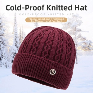 Close-up of wine red knit winter hat with thick fleece lining and decorative metal charm