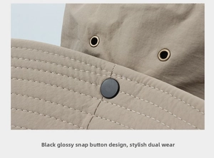 Detail of khaki sun hat featuring metal vents, white stitching, and a black snap button