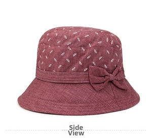 Détail d'un chapeau de soleil bordeaux avec motif de feuilles blanches et nœud