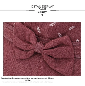 Détail du chapeau de soleil rouge foncé avec motifs de feuilles et un nœud décoratif