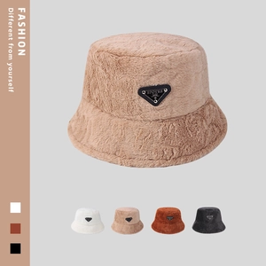 Detailansicht der flauschigen Fischerhüte mit Dreieckslogo in Beige, Weiß und Schwarz