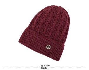 Detailed view of wine red cable knit beanie featuring thick wool yarn and a metal number five badge