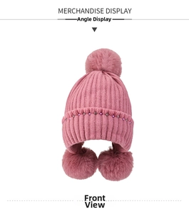 Pink knit trapper hat detail featuring plush fur pom-poms and elegant beaded trim decorations
