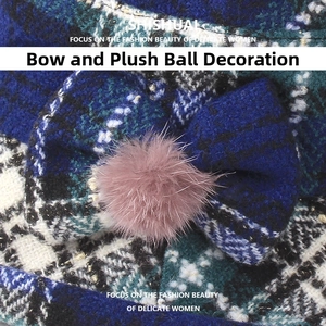 Detail of plaid bucket hat featuring a stylish bow and pink faux fur pom-pom ornament