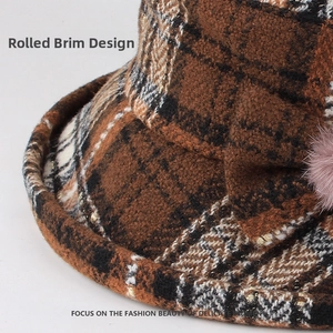 Detail view of the rolled brim design and soft pink fur ball on the plaid bucket hat