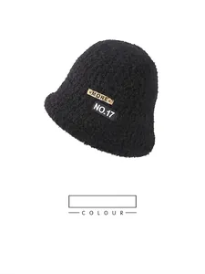 Detail view of the black plush bucket hat featuring a decorative MORE leather patch