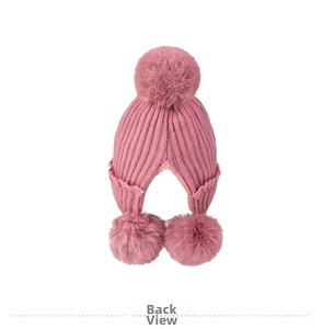 Detail of pink knitted beanie featuring faux fur pom-poms and delicate bead accents