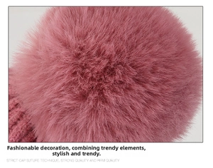 Close-up macro detail of soft fluffy pink rabbit fur pom-pom on the knitted beanie hat