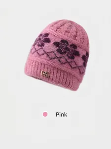 Detailed close-up of pink knit hat with floral jacquard and decorative metal buckle