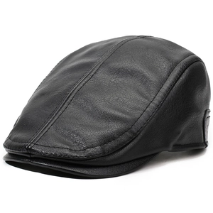 Close-up of black leather newsboy cap showing detailed pebble grain texture and stitching