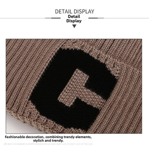 Dettaglio della maglia spessa marrone e della trama jacquard con lettera C sul berretto