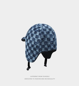 Close-up of checkerboard aviator hat with distressed denim fabric and earflap buckle