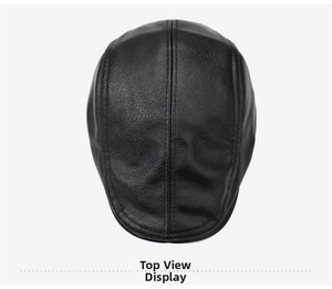Top view of black leather newsboy cap showing pebble grain texture and stitched seams
