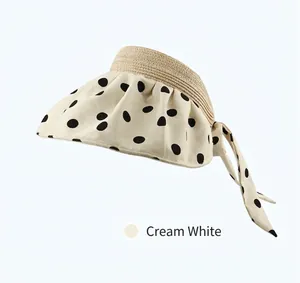 Detail of ivory sun hat with black polka dot fabric brim and woven straw top crown