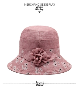Detailed close-up of pink cotton sun hat with white daisy print and handmade floral ornament