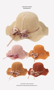 Detail of knitted straw sun hat featuring a satin bow and crystal buckle embellishment