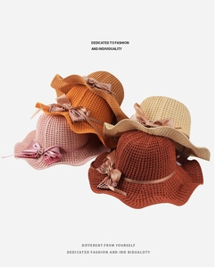 Close-up of crochet sun hats in pink, orange, beige and red with bow and buckle details