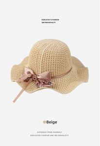 Detail of beige sun hat featuring a bow with rhinestones and houndstooth ribbon