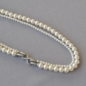Dettaglio della chiusura a infinito con zirconi su una collana di perle a doppio filo
