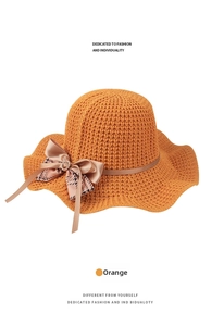 Detail of orange knitted sun hat with wave brim and pearl rhinestone bow buckle