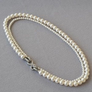 Dettaglio della collana di perle a doppio strato con fibbia infinity d'argento e cristalli