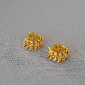 Detail of gold zircon olive leaf hoop earrings with micro-pave crystals on fabric