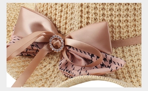 Detail of knitted sun hat with champagne satin bow and sparkling rhinestone buckle