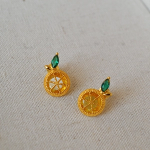 Close-up of gold-plated lemon stud earrings with yellow cubic zirconia and green leaf detail