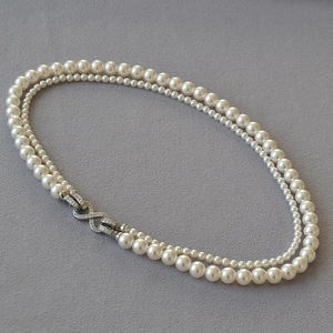 Dettaglio macro di una collana di perle a due strati con chiusura a infinito scintillante