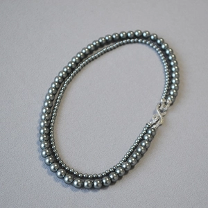 Dettaglio della collana di perle grigio scuro a due fili con chiusura di cristalli