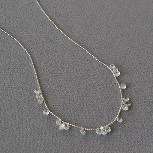 Sparkling silver beaded flower necklace with drop crystals on textured fabric
