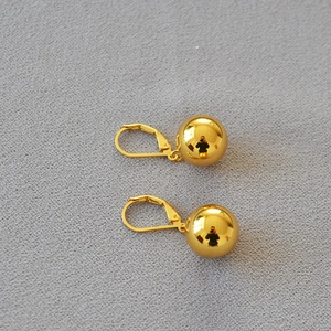 Detailed view of polished hollow gold plated ball earrings with secure lever-back closure