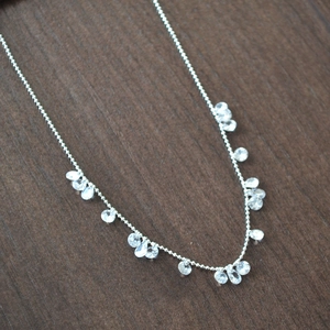 Elegant silver bead necklace featuring sparkling pear-cut crystal charms on a wood surface