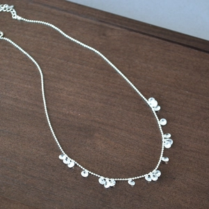 Detail of silver beaded necklace featuring multiple sparkling zircon teardrop pendants