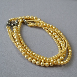 Détail d'un collier de perles dorées à cinq couches avec fermoir argenté multi-rangs