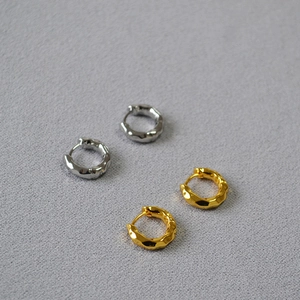 Detailed view of gold and silver small hoop earrings with irregular hammered lava texture