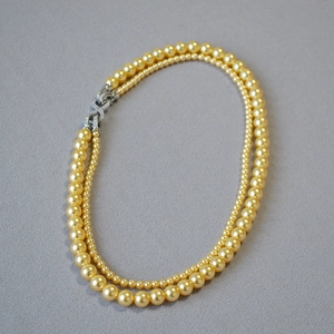 Dettaglio macro della collana di perle champagne con chiusura a forma di otto brillante