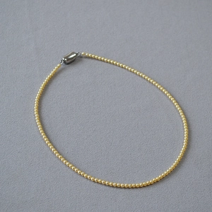 Détail du collier de perles dorées avec un fermoir magnétique élégant en argent brillant