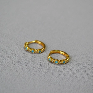 Detailed close-up of gold plated brass hoop earrings with turquoise and zircon stones