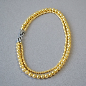 Dettaglio collana di perle dorate a doppio filo con chiusura a 8 ricoperta di cristalli