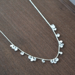 Detail of silver bead chain necklace featuring multiple dangling faceted crystal charms