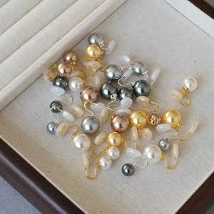 Élégants clips d'oreilles en perles rondes de plusieurs couleurs sur un plateau bois