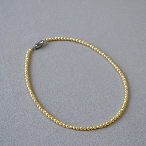 Détail d'un collier de perles dorées rondes élégantes avec fermoir métallique minimaliste