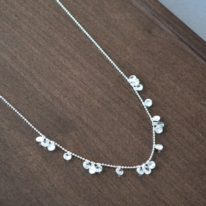 Detail of silver bead chain necklace with dangling clear cubic zirconia teardrop charms