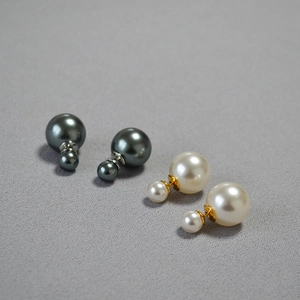 Detail of elegant double-sided pearl stud earrings in cream white and dark grey finish